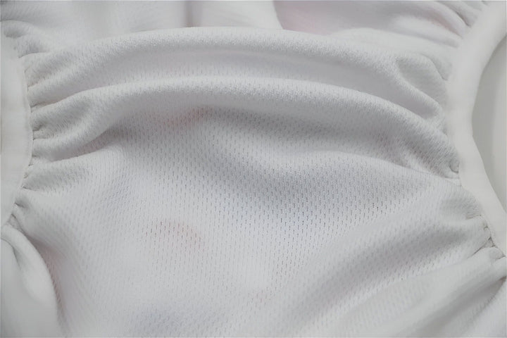 Image d'une couche lavable à poche avec un motif d'animaux comprenant des girafes, des éléphants et des canards sur fond blanc. Les élastiques aux cuisses sont visibles.