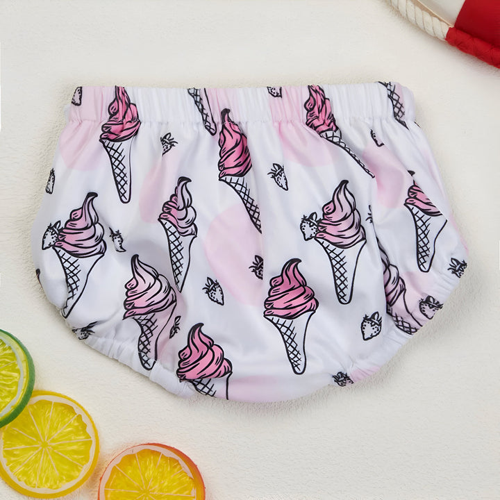 Culotte de bébé blanche avec un imprimé de cornets de glace rose et de fraises noires. Des tranches de citron jaune, d'orange et un anneau de sauvetage sont inclus.