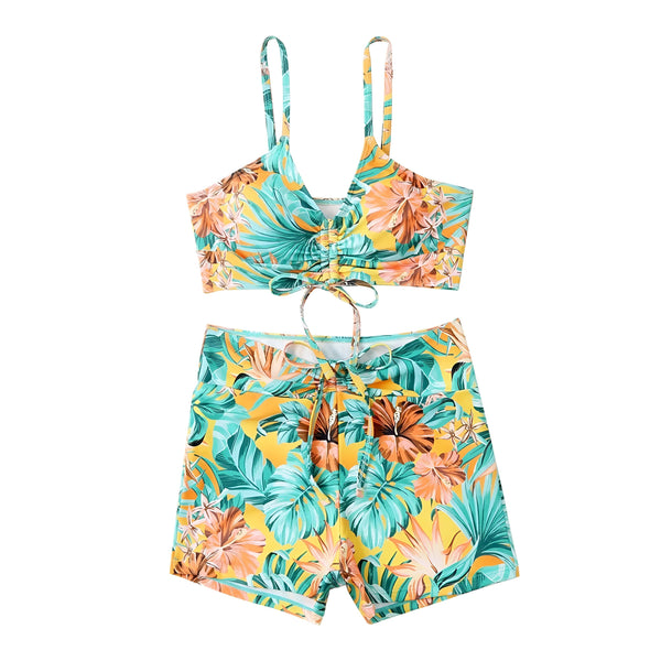Femme en maillot de bain deux pièces avec imprimé floral tropical, comprenant un haut noué à bretelles et un short de bain assorti.