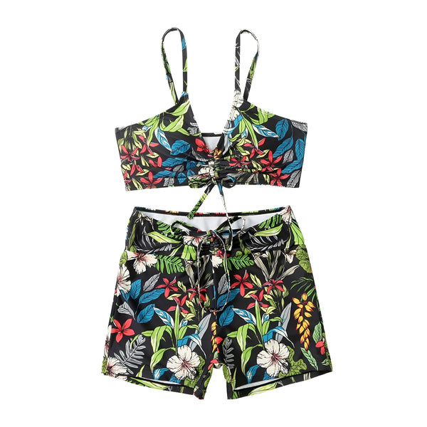 Femme portant un maillot de bain deux pièces à motif floral rose et noir. Haut à nouer au centre, short taille haute avec cordon. Tenue de plage tendance.