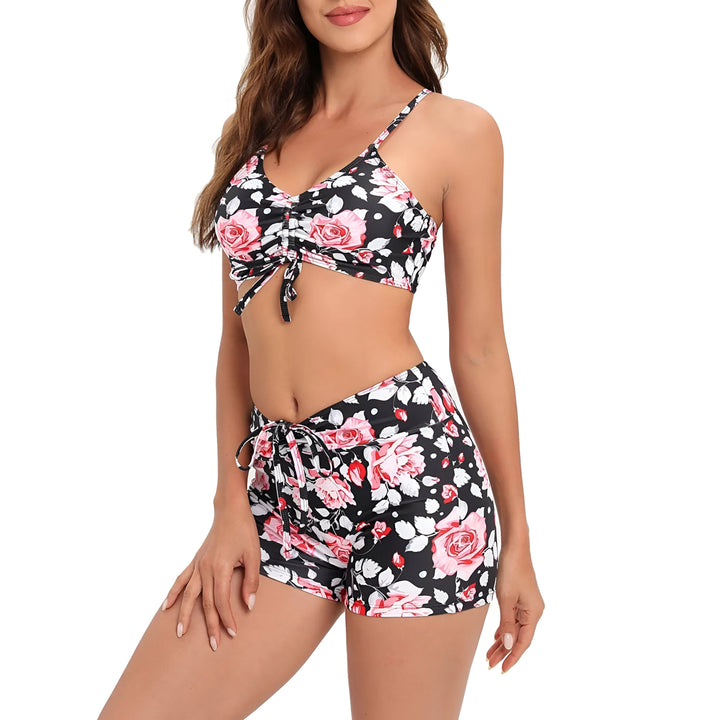 Femme portant un ensemble de bikini et short assorti à imprimé floral tropical jaune, turquoise et orange, souriant.