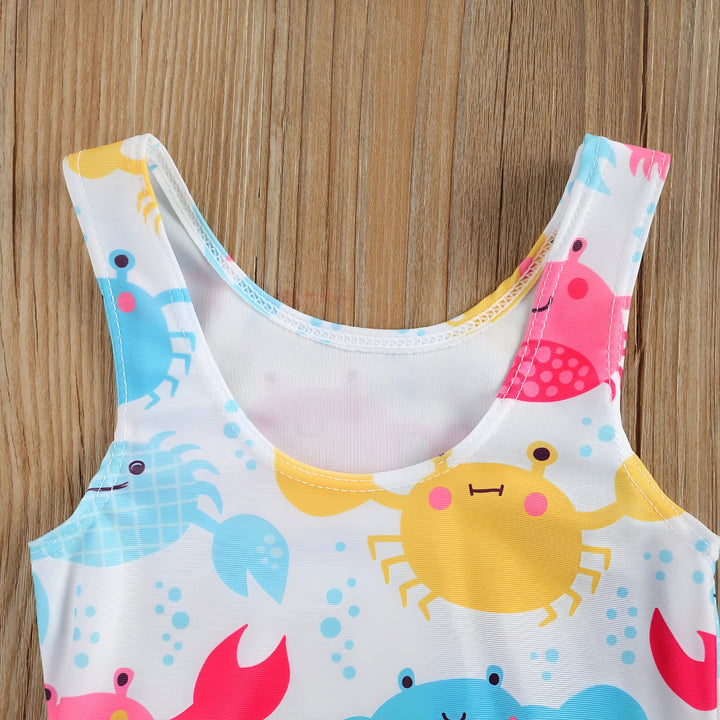 Maillot de bain bébé blanc à imprimé crabe coloré, bouée de sauvetage et décoration en bois sur fond bois. Vêtement d'été pour enfant.