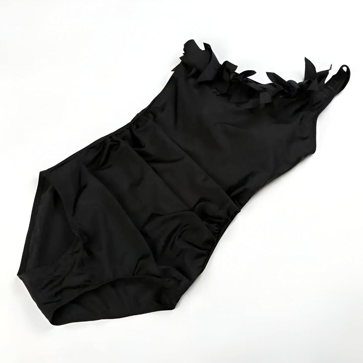 Maillot de bain une pièce noir avec volants sur une épaule. Élégant, féminin et parfait pour la plage ou la piscine. Mode été.