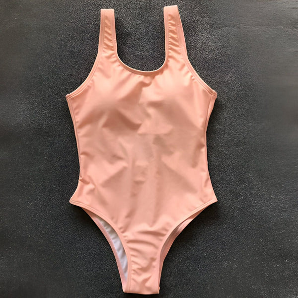 Image d'un maillot de bain une pièce blanc avec bordure pêche. Le maillot a des bonnets intégrés et est posé sur un fond gris foncé.