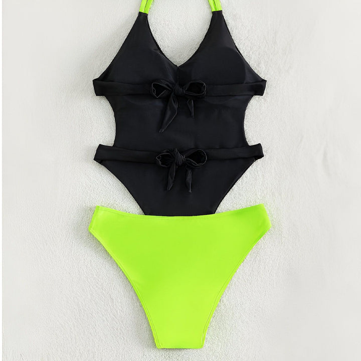 Image d'un maillot de bain noir une pièce avec un papillon coloré, associé à un chapeau de paille et des lunettes de soleil roses sur une surface blanche.