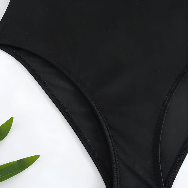Haut de maillot de bain noir avec bretelles ornées de perles dorées, bustier structuré avec décolleté plongeant. Style élégant et sophistiqué.
