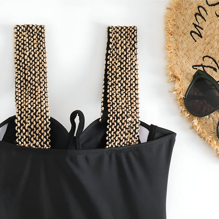 Maillot de bain noir une pièce avec des détails dorés sur les bretelles et à la taille, design élégant et tendance pour la plage ou la piscine.