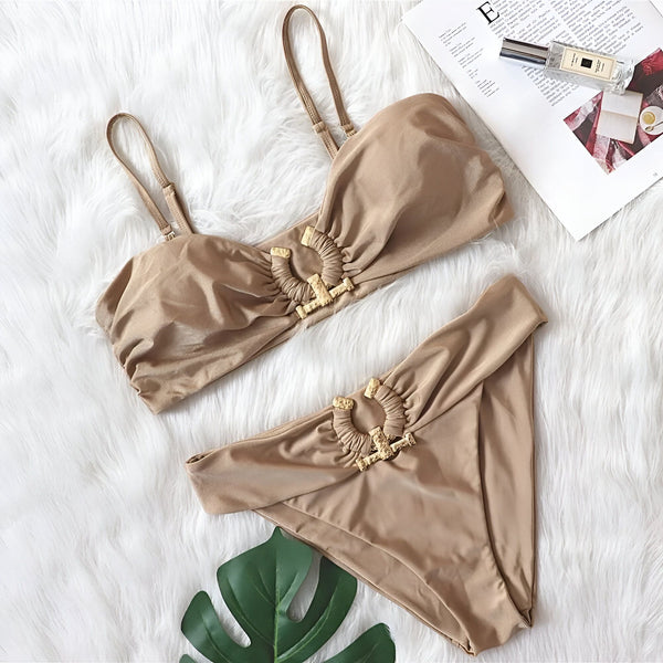 Maillot de bain deux pièces vert fluo avec détails dorés, posé sur une couverture en fausse fourrure blanche avec un magazine et une bouteille de parfum. Idéal pour la plage, la piscine et les vacances d'été.