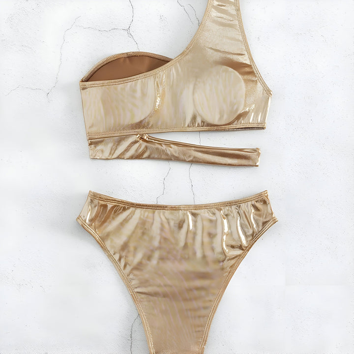 Vue aérienne d'un maillot de bain doré une pièce, lunettes de soleil, short en jean, brosse à cheveux et chapeau de paille sur fond blanc. Préparation pour la plage et les vacances d'été.