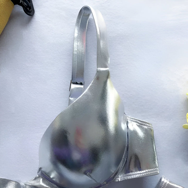 Image d'un maillot de bain argenté à deux pièces, présenté avec un sac jaune et un bouquet de fleurs jaunes sur un fond blanc. Accessoires de plage tendance.