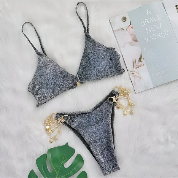 Défilé de mode : femme portant un bikini scintillant noir avec chaînes dorées sur les hanches. Vêtement de bain tendance, accessoire de mode.