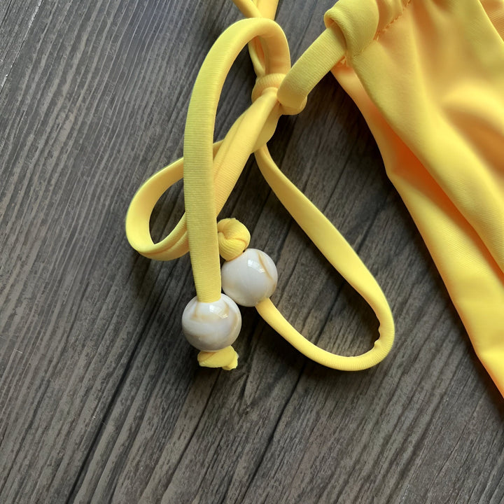 Ensemble de bikini jaune vif, haut triangle et bas à nouer. Mode d'été, prêt pour la plage, style tendance.