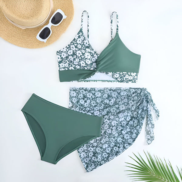 Vue rapprochée d'un haut de bikini vert foncé avec un motif floral blanc. Bretelles réglables visibles. Idéal pour l'été et les vacances.