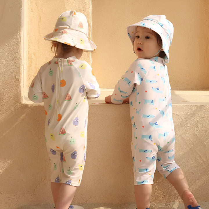 Combinaison de bain pour bébé avec motif de fruits amusants. Illustration d'un vêtement de protection solaire pour enfants. Barboteuse blanche à manches longues avec imprimé pastèque, citron et orange. Vêtement de plage pour enfant.