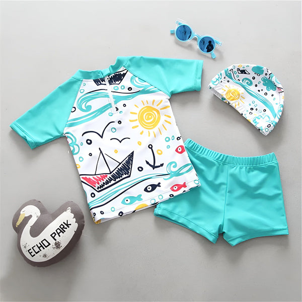 Gros plan sur un bonnet de bain blanc avec des motifs de vagues turquoise, de bateau à voile, de bulles et de soleils jaunes. Idéal pour les enfants.