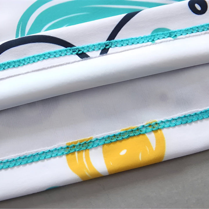 Gros plan sur le col turquoise et le motif de dents de requin rouge et noir sur un maillot de bain pour enfant.