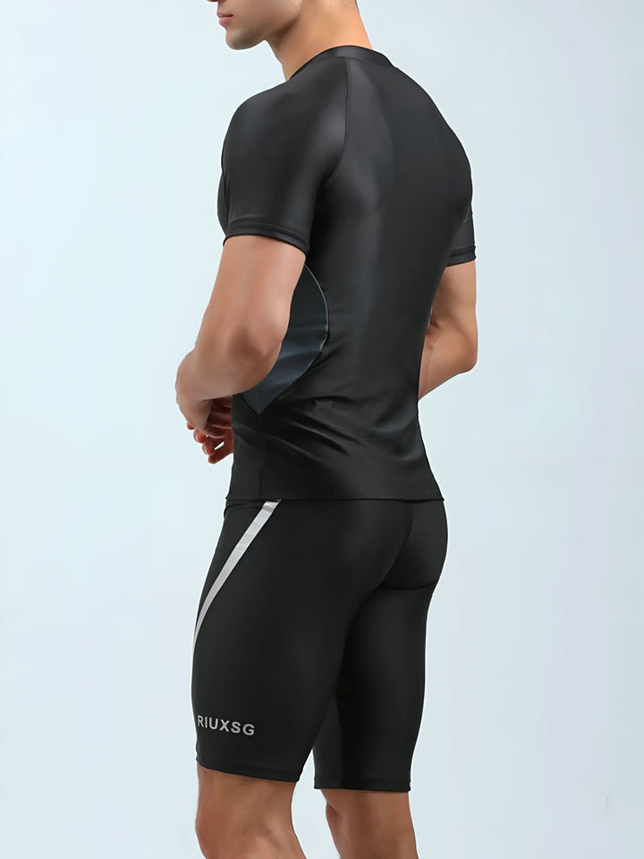 Homme en tenue de sport noire moulante, t-shirt manches courtes et short cycliste, idéal pour l'entraînement ou la course. Conception athlétique moderne et élégante.