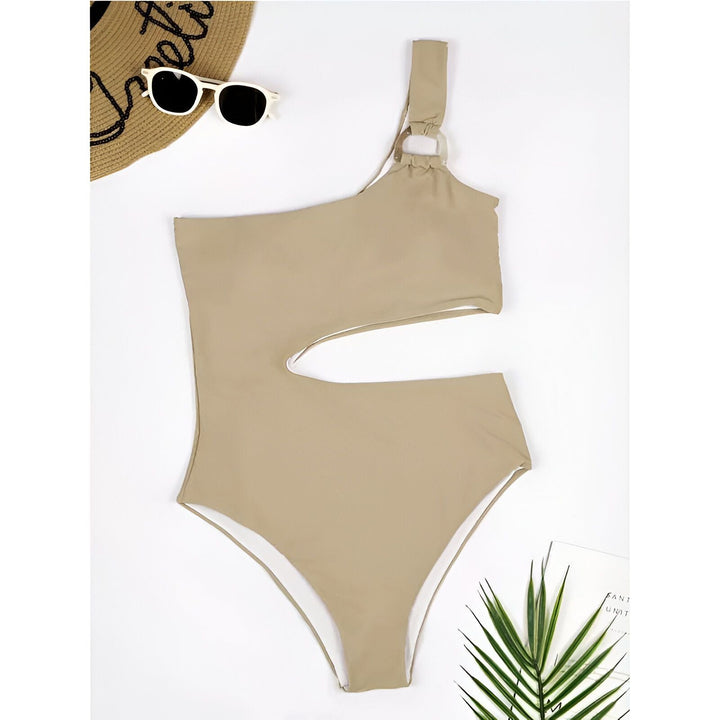 Maillot de bain une pièce noir avec découpe latérale et anneau décoratif sur la bretelle. Chemise blanche ample sur les épaules, collier doré.