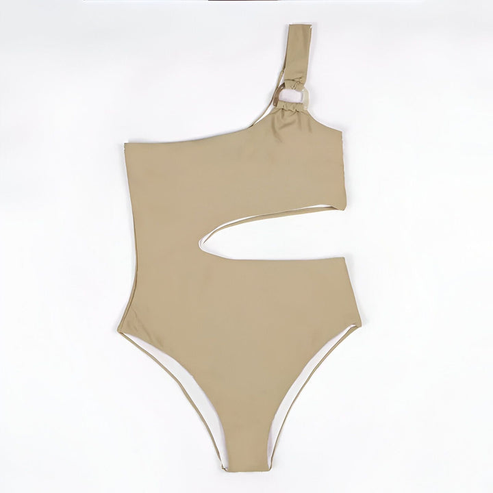 Une femme portant un maillot de bain une pièce beige avec une découpe à la taille et une chemise blanche ouverte. Elle porte un collier doré. Mode estivale, style de plage.