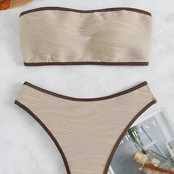 Image d'un ensemble de bikini noir avec des bordures blanches, comprenant un haut bandeau et une culotte taille haute.