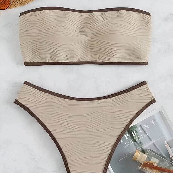 Image d'un ensemble de bikini noir avec des bordures blanches, comprenant un haut bandeau et une culotte taille haute.