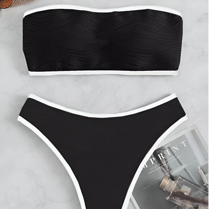Image d'un maillot de bain deux pièces noir et blanc à motif texturé, composé d'un haut bandeau et d'une culotte assortie. Idéal pour la plage ou la piscine.