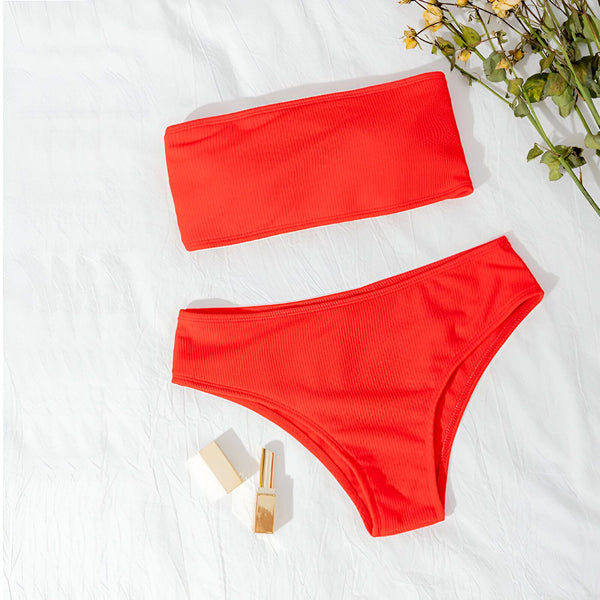 Maillot de bain deux pièces turquoise côtelé sur fond en bois, avec livre et rouge à lèvres assorti. Parfait pour l'été et la plage.