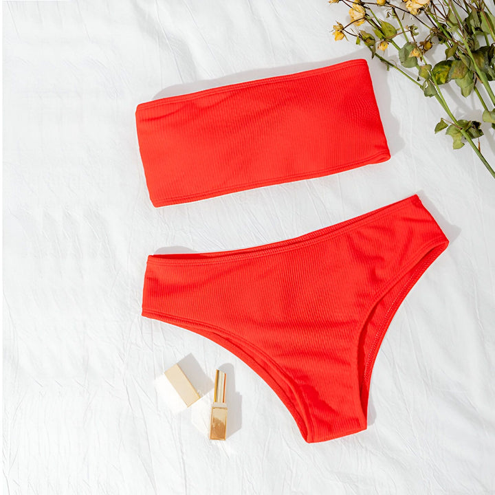 Maillot de bain deux pièces turquoise côtelé sur fond en bois, avec livre et rouge à lèvres assorti. Parfait pour l'été et la plage.