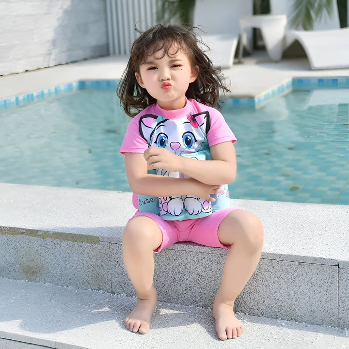 Maillot de bain enfant motif Batman bleu avec tournesol et étoiles de mer sur fond de petites pierres blanches. Vêtement de plage pour garçon.