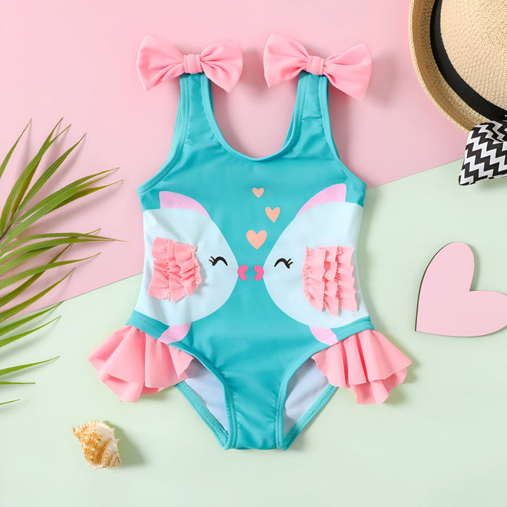 Gros plan d'un maillot de bain pour enfants turquoise et blanc avec des motifs de lapins qui s'embrassent et des volants roses. Des cœurs roses flottent au-dessus des lapins. Idéal pour les vacances à la plage et les journées ensoleillées.