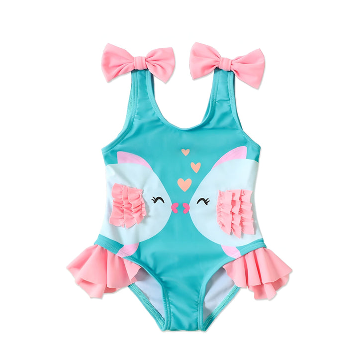 Gros plan d'un maillot de bain turquoise pour enfant avec des nœuds roses sur les bretelles, et des motifs d'animaux. Idéal pour la plage ou la piscine.