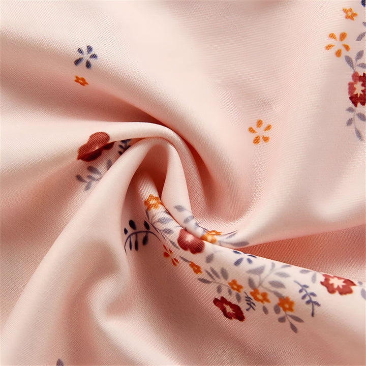 Vue rapprochée d'une robe d'été rose pâle à motifs floraux avec des bretelles à nouer. Tissu léger et aéré, idéal pour les chaudes journées. Style décontracté et féminin.