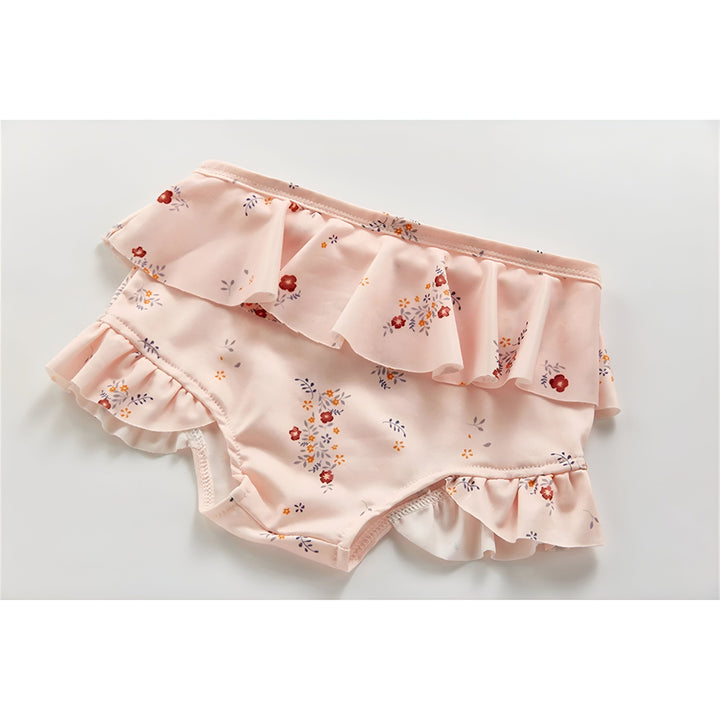 Culotte de bain rose pâle à motif floral avec volants pour bébé, vue de dessus. Idéal pour la plage et la piscine. Mode enfant estivale.