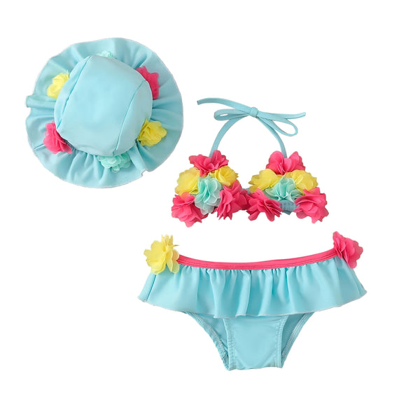 Ensemble de maillots de bain pour filles avec chapeaux et lunettes de soleil. Les maillots sont décorés de fleurs colorées. Le fond est en bois clair.