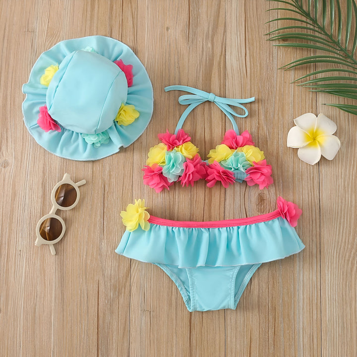 Haut de bikini rose avec des fleurs jaunes, roses et turquoise en tissu sur un fond en bois.