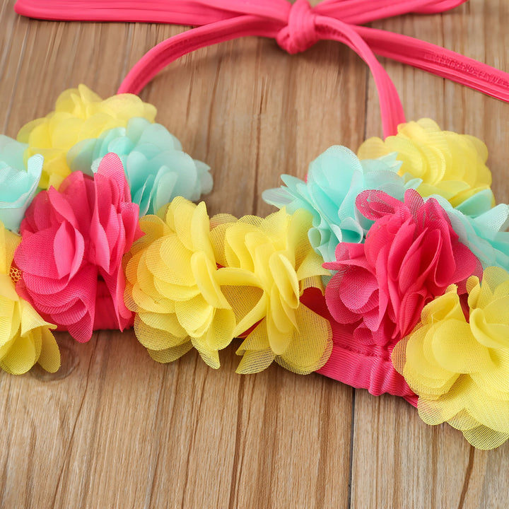 Ensemble de bain pour enfant bleu avec fleurs roses et jaunes, chapeau assorti et lunettes de soleil. Idéal pour la plage et la piscine.