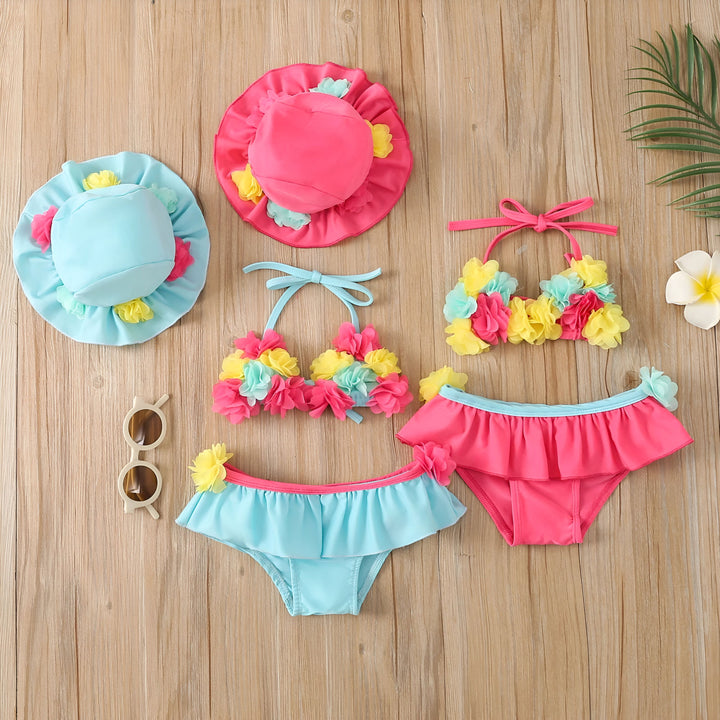 Ensemble de bain bleu clair pour bébé avec fleurs roses, jaunes et turquoise, incluant un chapeau assorti. Vêtements de plage pour enfants.