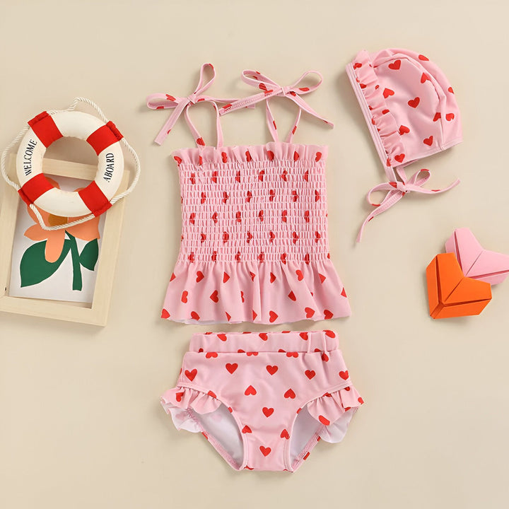 Culotte de maillot de bain rose pâle à motifs de coeurs rouges et volants blancs. Vêtement pour enfants.