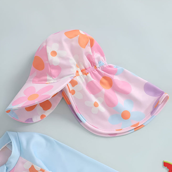 Chapeau de soleil pour enfant avec motif floral rose, orange et bleu, et un vêtement de plage bleu clair. Idéal pour protéger du soleil avec style.