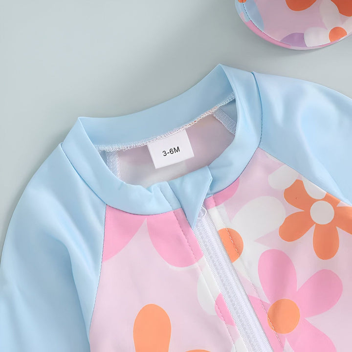Maillot de bain bébé fleuri rose et bleu ciel avec fermeture éclair et chapeau assorti pour la plage. Accessoires : coquillage, tournesol, citron, pastèque.
