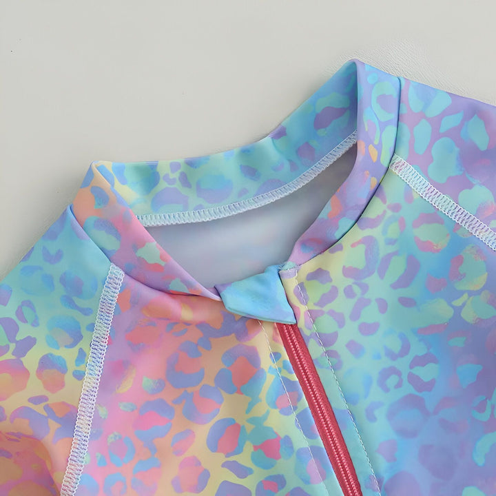 Gros plan sur le col et la fermeture éclair rose d'un maillot de bain pour enfant avec un motif léopard coloré dans des tons pastel, idéal pour la plage ou la piscine.