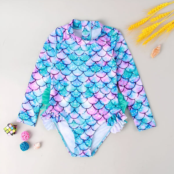 Gros plan d'un slip de bain blanc avec imprimé écailles de sirène turquoise, rose et violet, bordé de bleu clair.