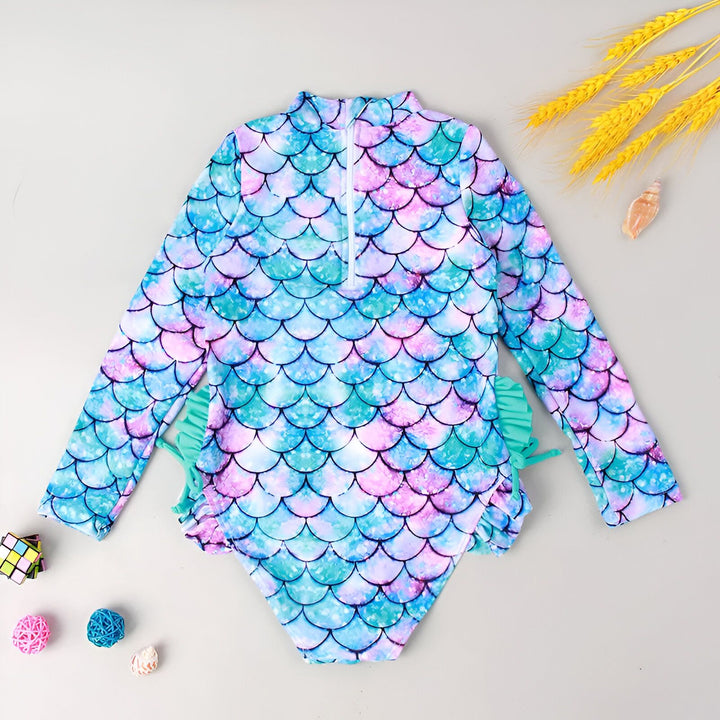 Maillot de bain une pièce pour fille avec manches longues turquoise et motif écailles de sirène multicolores. Fermeture éclair sur le devant. Accessoires de plage décoratifs.