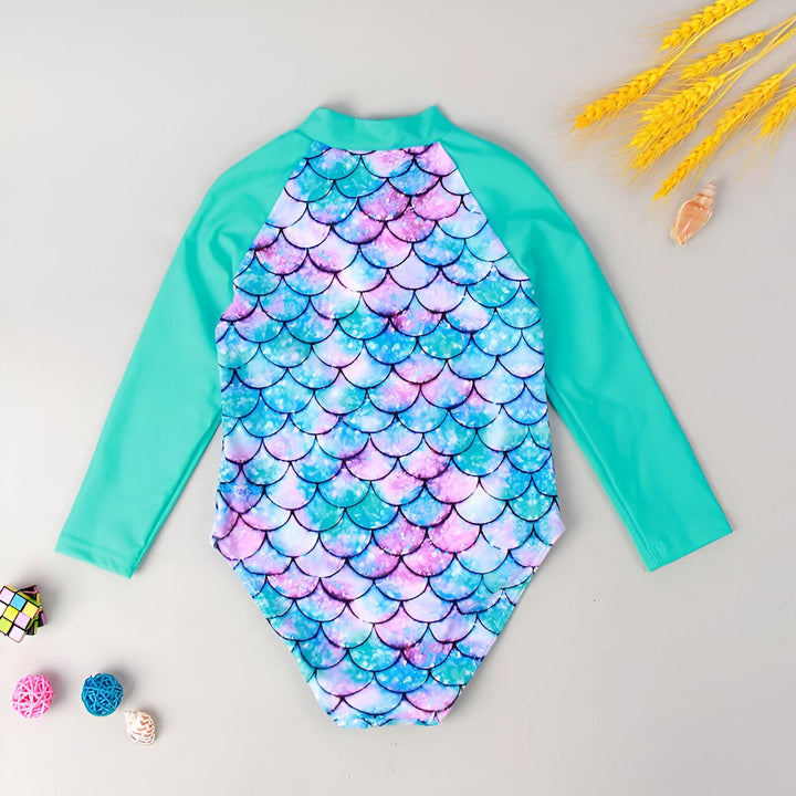 Combinaison de bain pour enfant à manches longues, motif écailles de sirène aux tons bleus, violets et roses, avec des volants turquoise et blancs.