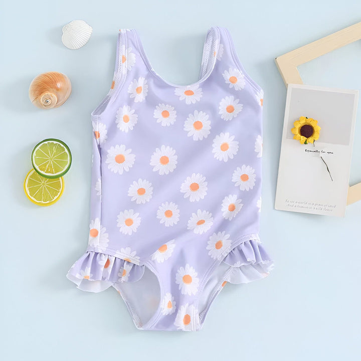 Maillot de bain une pièce lilas à motif de marguerites blanches pour enfant, avec volants. Accessoires de plage : coquillages, citron, fleur. Idéal pour l'été et les vacances.