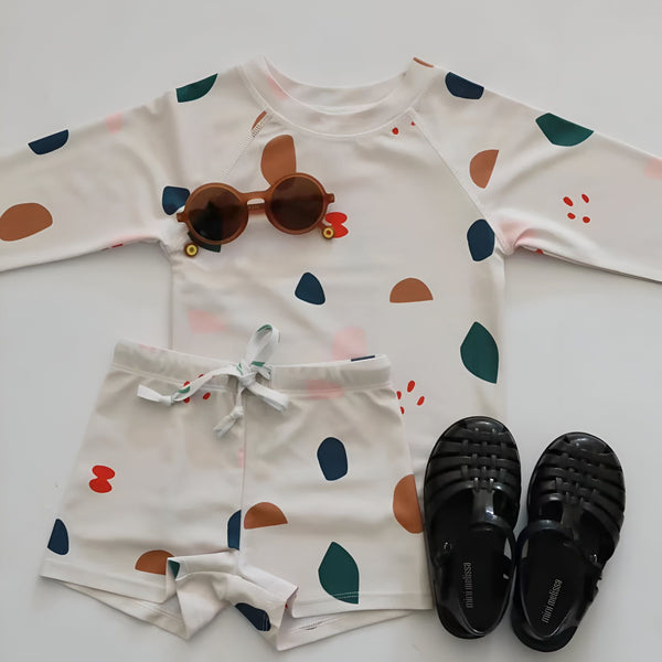 Ensemble de pyjama pour enfant avec motif de dinosaures. Haut à manches longues et short assorti. Motif gris avec dinosaures, feuilles et fleurs. Vêtement de nuit confortable et amusant pour les enfants.