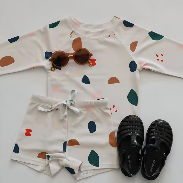 Ensemble de pyjama pour enfant avec motif de dinosaures. Haut à manches longues et short assorti. Motif gris avec dinosaures, feuilles et fleurs. Vêtement de nuit confortable et amusant pour les enfants.