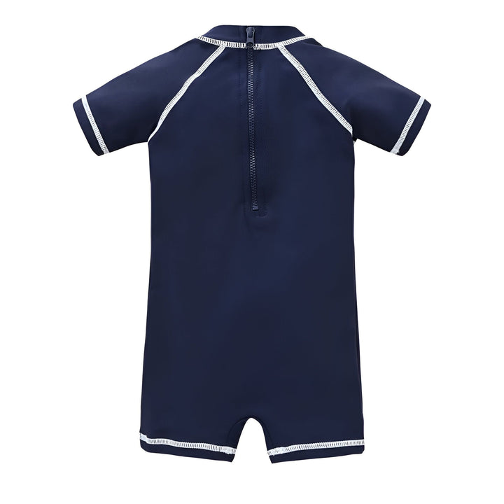 Gros plan d'un vêtement bleu avec des motifs d'oiseaux stylisés blancs et noirs. Une bordure bleu marine et une couture blanche zigzag visible. Texture détaillée du tissu.