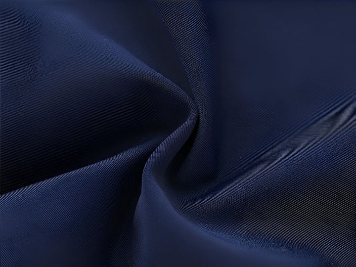 Gros plan sur un maillot de bain pour enfant. Le tissu est bleu ciel avec des motifs d'oiseaux et de vagues blanches. Les bords sont bleu marine avec des coutures blanches.