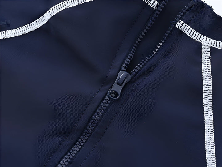 Gros plan sur un maillot de bain de sport bleu marine avec un motif de vagues, d'oiseaux et de palmiers bleu ciel. Détail du col et des coutures blanches. Vêtement pour enfant.